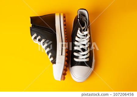 New black and white canvas sneakers on yellow background New black and white canvas sneakers on yellow background 107206456