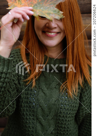 Laughing red-haired middle-aged woman, closed eyes and maple leaf Laughing red-haired middle-aged woman, closed eyes and maple leaf 107206624
