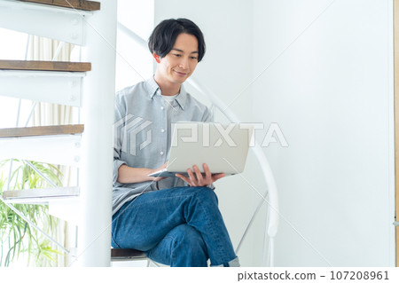 Young woman relaxing on the stairs while looking at a computer 107208961
