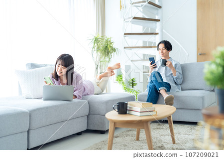 Young couple relaxing in the living room looking at computer and smartphone 107209021