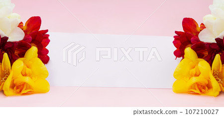 Bouquet of yellow and red freesias with paper for text. Holidays, International women's, Mother's day, birthday, March 8. Banner. Copy space 107210027
