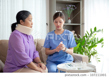 Caregiver or nurse check neck of senior woman and explaining drug in living room. Caregiver or nurse check neck of senior woman and explaining drug in living room. 107211001