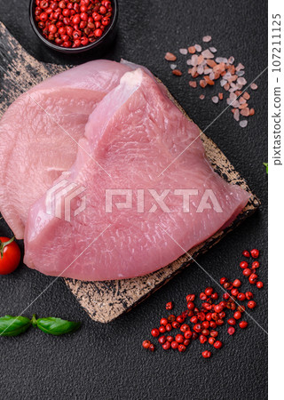 Raw turkey meat in the form of slices with salt, spices and herbs 107211125