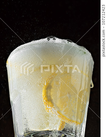 Cold drink on a black background. One glass with lemonade or mojito cocktail with lemon and mint. Close up 107212423