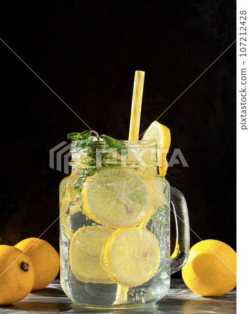 One glass with lemonade or mojito, a cocktail with lemon and mint. Cold drink on a black background. Copy space, close up. 107212428