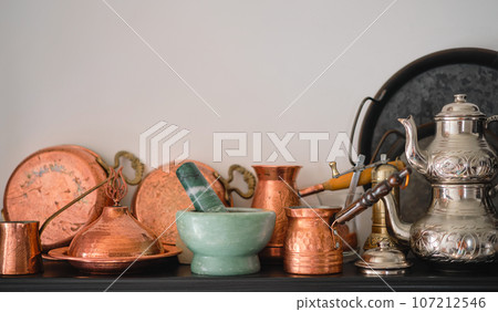 Handmade copper utensils, Turkish traditional tableware on a shelf in the kitchen at home, selective focus, copy space for text 107212546