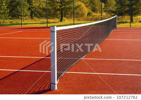 Black tennis net over a red playground outdoors Black tennis net over a red playground outdoors 107212762