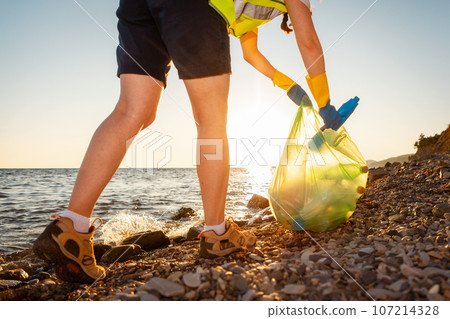 Environmental conservation. Bottom view of woman volunteer picking up garbage at beach. Concept of ocean's pollution and recycling garbage 107214328