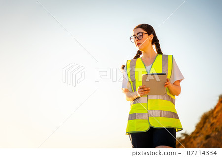 Inspection environmentalist. Bottom view of volunteer woman wearing vest and using pad for analyzing water. In background is sky. Copy space. Concept of air pollution and ecology 107214334