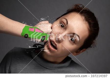 the concept of car accidents, insurance claims . close-up of the accident.The girl is hit by a green car .a punch in the face of a young girl .Fist in the form of drawn machines.close -up 107214397