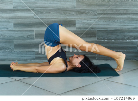 plow pose variation or halasana yoga with ukrainian woman making it indoors 107214969