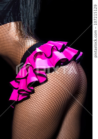 Female sexy figure legs in mesh tights and pink skirt and beautiful butt on black background 107215129