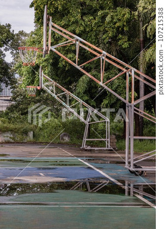 Two basketball wooden backboards with the hoop metal rings and the white and red net on the cement court are at old cemetery park. Two basketball wooden backboards with the hoop metal rings and the white and red net on the cement court are at old cemetery park. 107215388