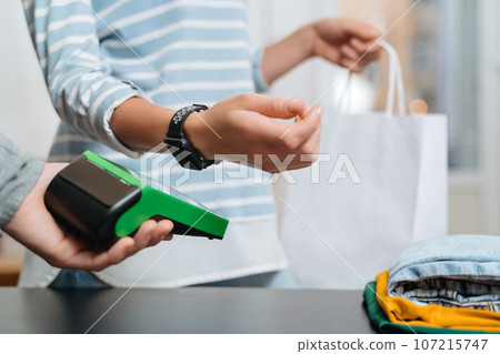 Closeup of woman paying for purchase by smart watch with nfc technology 107215747