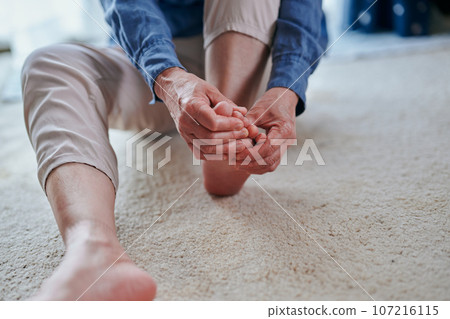 Senior woman with sensitivity to cold massaging her feet Senior woman with sensitivity to cold massaging her feet 107216115