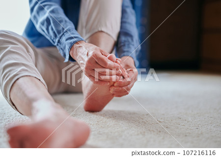 Senior woman with sensitivity to cold massaging her feet 107216116