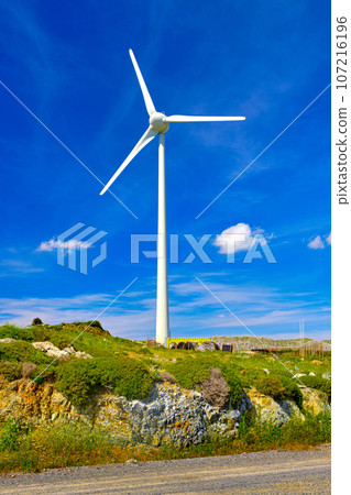 One wind turbine on top of green hill on sunny day. Local energy production, alternative electricity source, sustainable energy technology, green, eco-friendly power supply. Crete island, Greece. One wind turbine on top of green hill on sunny day. Local energy production, alternative electricity source, sustainable energy technology, green, eco-friendly power supply. Crete island, Greece. 107216196