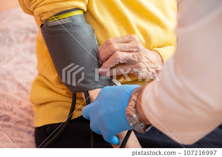 A doctor using a sphygmomanometer with a stethoscope revealed arterial hypertension in a patient in the hospital. A doctor using a sphygmomanometer with a stethoscope revealed arterial hypertension in a patient in the hospital. 107216997