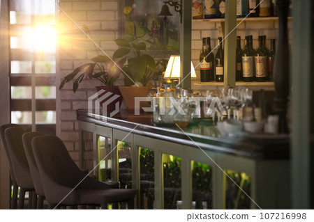 Part of the interior of a cozy restaurant with a bar counter with glasses and a cabinet for wine. 107216998