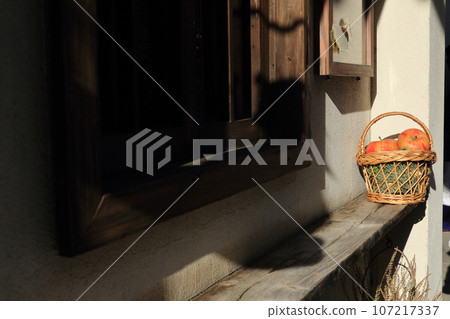 A basket placed by the window with apples in it 107217337
