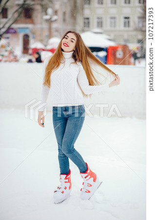 Girl in a winter city. Beautiful lady in a white sweater. Woman in a ice arena 107217393