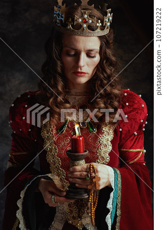 medieval queen in red dress with candle and crown 107219222