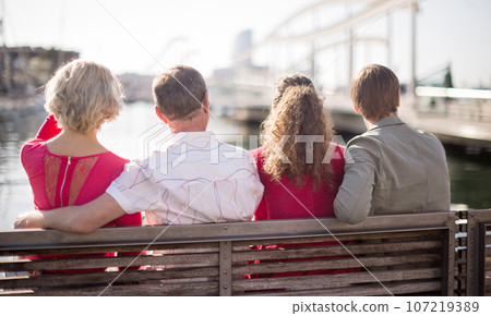 Courists sitting on bench in port in European city Courists sitting on bench in port in European city 107219389