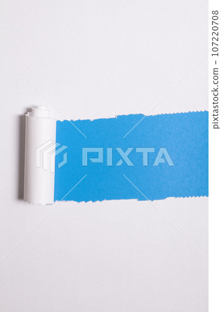 Torn paper with opening showing blue background. 107220708