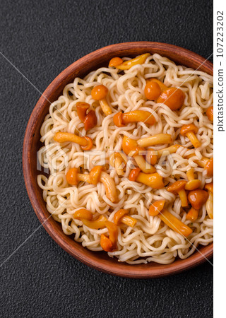 Delicious Asian cuisine dish with rice noodles, peppers, mushrooms and spices Delicious Asian cuisine dish with rice noodles, peppers, mushrooms and spices 107223202