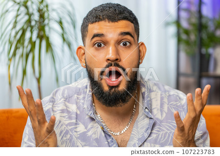 Excited Arabian man surprised, shocked by sudden victory, good win news, celebrating, wow reaction 107223783