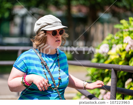 Outdoor portrait of a 40 yo woman with the Down Syndrome, wearing sunglasses and a hat, Belgium Outdoor portrait of a 40 yo woman with the Down Syndrome, wearing sunglasses and a hat, Belgium 107223963