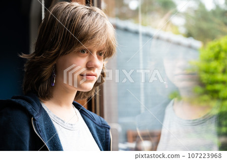 Portrait of a dreaming 15 year old girl looking through the window, Belgium 107223968