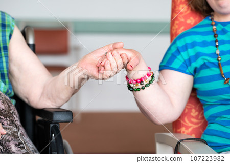 Close up of the hands of an 84 yo white woman and her 40 yo daughter with the Down Syndrome, Belgium Close up of the hands of an 84 yo white woman and her 40 yo daughter with the Down Syndrome, Belgium 107223982