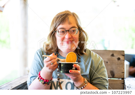 Portrait of a 40 yo woman with the Down Syndrome eating an ice cream, Belgium 107223997