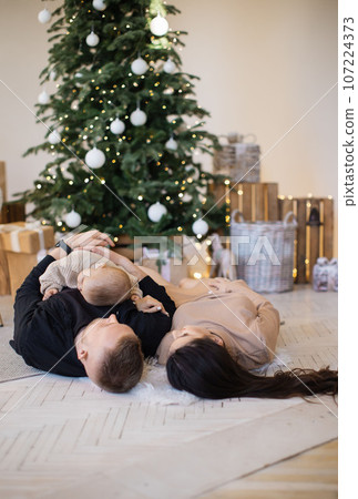 Mother, father and daughter lying on floor at decorated home 107224373