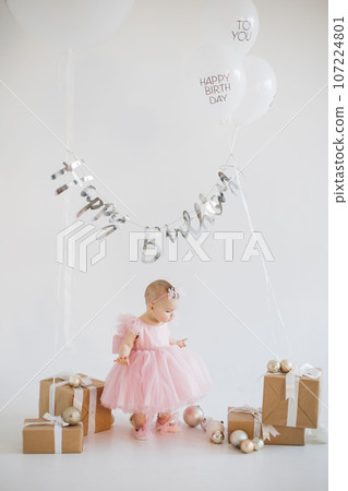 Lovely little girl celebrating birthday in decorated studio 107224801