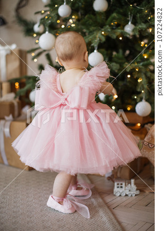 Toddler standing near decorated Christmas tree in studio Toddler standing near decorated Christmas tree in studio 107224822