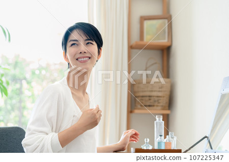 A woman doing skin care in her room 107225347