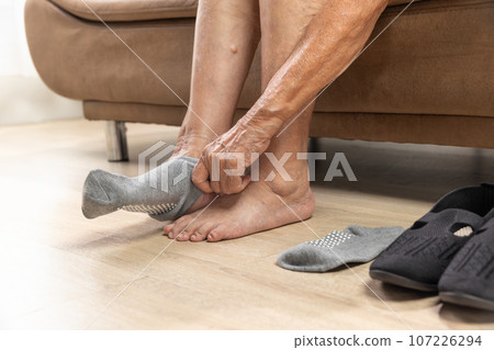 Elderly woman wear non slip grip socks for senior people who have trouble keeping their balance. Elderly woman wear non slip grip socks for senior people who have trouble keeping their balance. 107226294