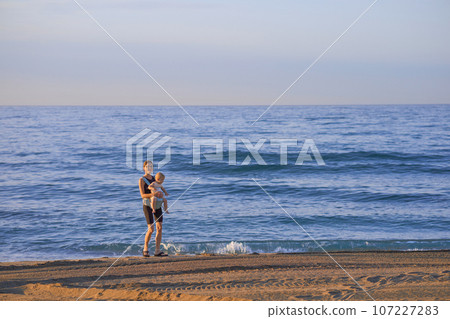 Mother and baby on the beach at sunset. Happy family on vacation. 107227283
