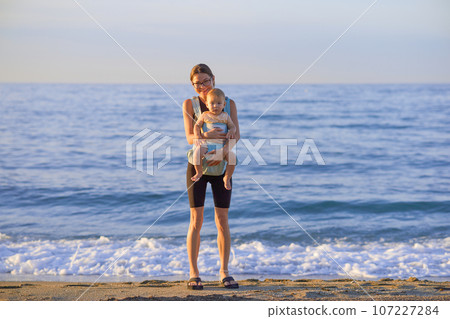 Mother and baby on the beach at sunset. Happy family on vacation. 107227284