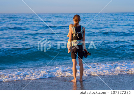 Mother and baby on the beach at sunset. Happy family on vacation. 107227285