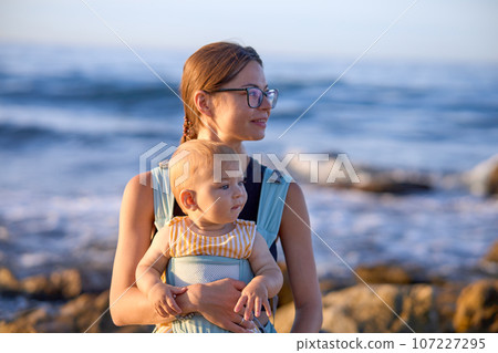 Mother and baby on the beach at sunset. Happy family on vacation. 107227295