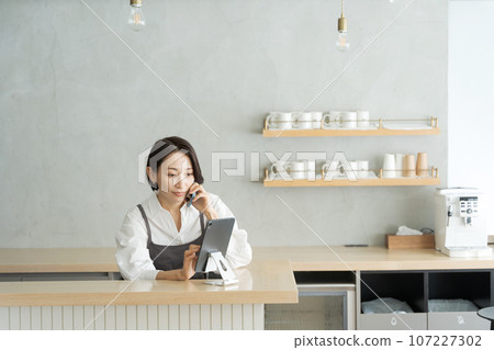 Staff answering the phone at a cafe Staff answering the phone at a cafe 107227302