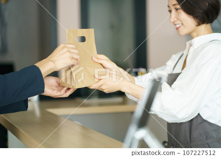 Cafe clerk and customer handing over products 107227512