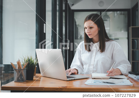 Beautiful woman using laptop while sitting at her working place. Concentrated at work.. 107227829