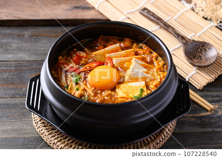 Korean spicy noodle soup with kimchi, tofu, egg and mushroom in Korean stone bowl 107228540