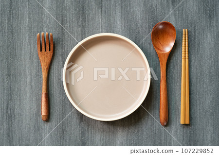 Kitchenware. dish, wooden spoon, fork, chopsticks on gray fabric background. top view, copy space 107229852