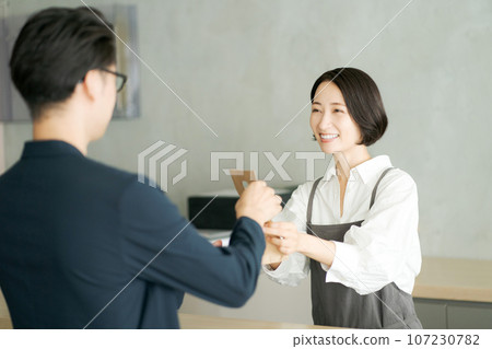 Cafe clerk and customer handing over products 107230782