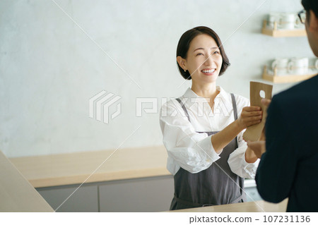 A woman in her 40s passing a paper bag A woman in her 40s passing a paper bag 107231136